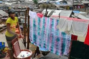 Dans le bidonville de Kroo à Freetown, une femme fait la lessive, le 13 août 2014. © AFP