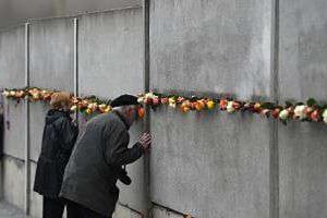 Des visiteurs regardent à travers les fentes d’un morceau de l’ancien Mur, le 9 novembre 2014. © AFP