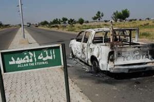 Une voiture de police brûlée est abandonnée sur une route à Damaturu, au Nigeria, en 2011. © AFP