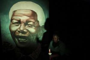 Une habitante de Soweto éclaire à la bougie une peinture murale de Nelson Mandela, le 4 décembre. © Siphiwe Sibeko/Reuters