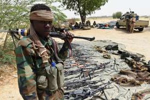 Un soldat tchadien monte la garde devant des armes de Boko Haram saisies à Malam Fatori. © AFP