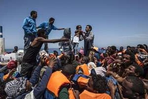 Des migrants à bord d’une embarcation en bois attendent d’être secourus au large de la Sicile. © Jason Florio/AFP
