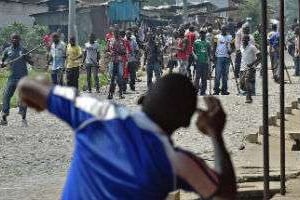 Un manifestant lance une pierre en direction de membres de la jeunesse du parti au pouvoir, à Bujum © Carl de Souza/AFP