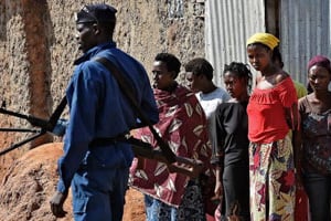 Des femmes regardent les policiers patrouiller à Bujumbura. © AFP