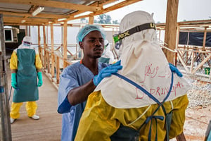 Un membre du personnel soignant  aide un de ses collègues à mettre sa combinaison de protection au mois de mars 2015 à Makeni. © Micheal Duff/AP/Sipa