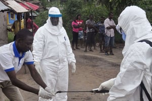 Des professionnels de la santé se désinfectent après  avoir fait des tests sanguins dans le village du Liberia où l’adolescent est mort de l’épidémie le 30 juin 2015. © Abbas Dulleh/AP/SIPA