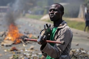 Un manifestant pointe une fausse arme vers des soldats lors d’une manifestation à Bujumbura en juin 2015. © Gildas Ngingo/AP/Sipa