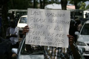 Un homme porte une pancarte à Bujumbura, le 20 octobre 2015, lors des funérailles d’un journaliste et de sa famille tués le 13 octobre 2015. © Landry Nshimiye/AFP