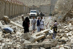 Des Yéménites marchent dans les décombres d’immeubles du quartier Al-Nahda dans la capitale, Sanaa, après des frappes aériennes menées par l’Arabie Saoudite © Mohammed Huwais/AFP