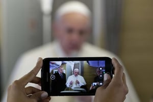 Un journaliste filme avec son téléphone le pape François à bord de l’avion qui le conduit au Kenya, le 25 novembre 2015. © Andrew Medichini/AP/SIPA