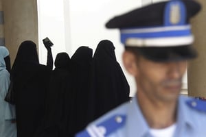 Un officier de police devant des proches des suspects dans l’affaire de l’attentat du café Argana, près de Rabat, le 6 octobre 2011.