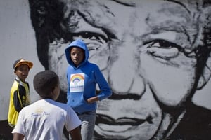 Des enfants sud africains jouent devant une fresque murale représentant Nelson Mandela, le 2 mai 2014, dans le quartier Soweto de Johannesburg © Ben Curtis / AP / SIPA