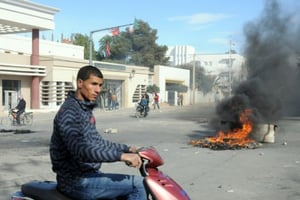 Un jeune Tunisien passe devant des pneus brûlés lors de heurts avec la police, le 20 janvier 2016 à Kasserine. © AFP