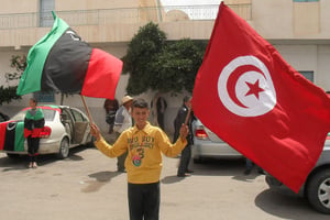 Un jeune Libyen brandit le drapeau tunisien et celui de la Libye libre à Tataouine (Tunisie). © Flickr/Magharebia