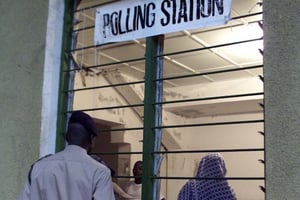 Un policier jette un coup d’œil à l’intérieur d’un bureau de vote en Gambie en 2001. © CHRISTINE NESBITT/AP/SIPA