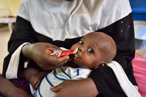 Une femme nourrit son enfant avec du « Plumpy nut » le 14 juin 2016. © Issouf Sanogo/AFP