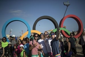 Des passants posent devant les anneaux olympique à la plage de Copacabana à Rio, le 31 juillet 2016. © Felipe Dana/AP/Sipa