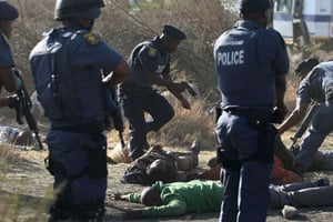 Des policiers sud-africains se tiennent près des corps de mineurs tombés à Marikana, le 16 août 2012. © Str/AP/SIPA