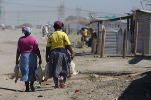 Des femmes longeant les habitations précaires de mineurs à Marikana. © Denis Farrell/AP/SIPA