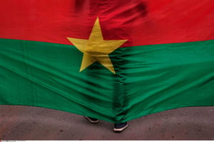 Un homme est adossé au drapeau national durant une cérémonie en souvenir des victimes des attentats de Ouagadougou  perpétrés le 15 janvier 2016. © Theo Renaut/AP/SIPA