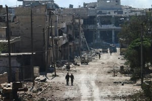Des combattants syriens pro-régime empruntent une rue de la ville d’Alep ravagée par les bombardements, le 9 septembre 2016. © GEORGE OURFALIAN/AFP