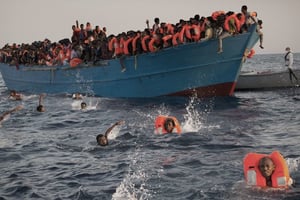 Migrants, most of them from Eritrea, jump into the water from a crowded wooden boat as they are helped by members of an NGO during a rescue operation at the Mediterranean sea, about 13 miles north of Sabratha, Libya. © Emilio Morenatti/AP/SIPA
