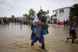 Un homme prête main-forte à une femme lors des inondations causées par l’ouragan Matthew, le 5 octobre 2016. © Dieu Nalio Chery/AP/SIPA