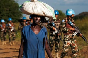 Une réfugiée marche aux côtés de casques bleus, près d’un camp de protection des civils (POC) de l’ONU à Djouba, le 4 octobre 2016. © Albert Gonzalez Farran/AFP