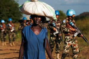 Une réfugiée marche aux côtés de Casques Bleus, près d’un camp de protection des civils (POC) de l’ONU à Juba, le 4 octobre 2016 © ALBERT GONZALEZ FARRAN/AFP