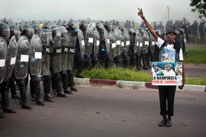Un militant de L’UDPS d’Etienne Tshisekedi fait face à la police anti émeute alors que cette dernière disperse les manifestants rassemblés devant l’aéroport de N’Djili à Kinshasa le 26 novembre 2011. © Gwenn Dubourthoumieu pour J.A.