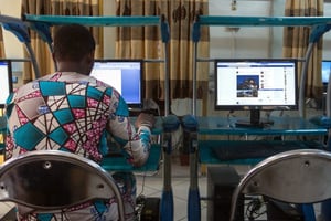 Un homme surfe sur Internet dans un cyber-café de Cotonou, au Bénin, le 24 février 2016. © Gwenn Dubourthoumieu pour Jeune Afrique