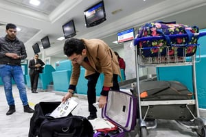 Un voyageur met son ordinateur dans son sac avant de s’envoler pour Londres à l’aéroport de Tunis le 25 mars 2017. © AFP/Fethi Belaid