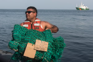 Un membre de l’équipage de l’Esperanza avec du matériel de pêche illégal saisi par les autorités guinéennes © Pierre Gleizes pour Greenpeace
