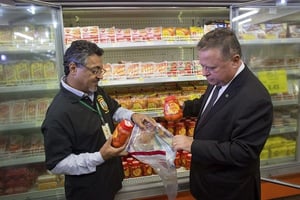 Le ministre brésilien de l’Agriculture, Blairo Maggi (à droite), accompagné d’un agent de l’inspection sanitaire, en train de prélevé un échantillon de viande pour des tests, le 22 mars 2017 à Brasilia, au Brésil. © Eraldo Peres/AP/SIPA