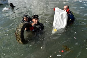 En équipement de plongée ou en tenue de plage, mains protégées par des gants, hommes, femmes et enfants se sont mués samedi 1er juillet 2017 en « éboueurs de la mer » sur une plage de l’est d’Alger jonchée de déchets. © RYAD KRAMDI / AFP