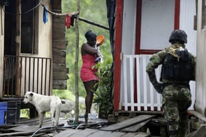 Une femme se lave pendant qu’un soldat des Forces spéciales de la Marine colombienne patrouille, à Buenaventura, le 28 mars 2014. © Fernando Vergara/AP/SIPA