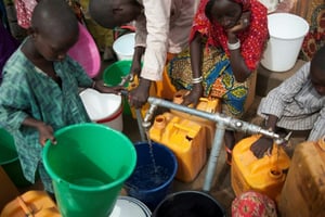 Des femmes et des enfants du camp de déplacés de Muna, à la périphérie de la grande ville de Maiduguri, capitale de l’État du Borno, au Nigeria, collectent de l’eau d’un puits le 30 juin 2016. © Stefan Heunis/AFP