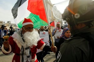 Un manifestant palestinien habillé en père Noël s’oppose à un membre des forces de l’ordre israélienne à Bethléem le 23 décembre 2017. © AFP
