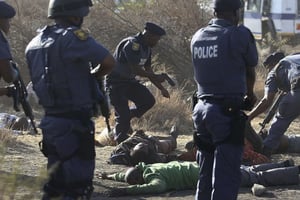 Des policiers sud-africains se tiennent près des corps de mineurs tombés à Marikana, le 16 août 2012. © AP/SIPA