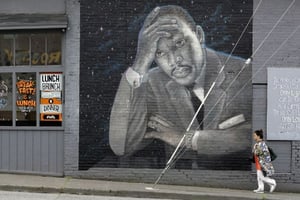 Une femme passe devant une grande peinture murale du pasteur Martin Luther King Junior sur le côté d’un restaurant, peint par l’artiste James Crespinel dans les années 1990 et restauré plus tard, le long de la route Martin Luther King Junior. À Seattle (États Unis), le 3 avril 2018 © Elaine Thompson/AP/SIPA