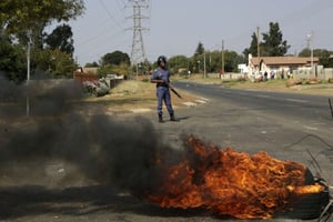 Un policier sud-africain face à des pneus brûlés, dans le township de Ennerdale, à Johanesburg, en Afrique du Sud, le 11 mai 2017. © Themba Hadebe/AP/SIPA