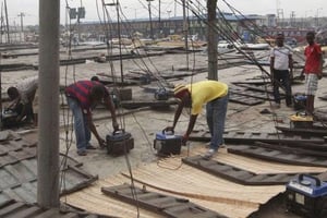 Des ouvriers réparant des générateurs sur les toits d’un marché de Lagos, au Nigeria, en 2010. © Sunday Alamba/AP/SIPA