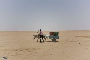 Un homme et son âne transportent des tonneaux d’eau vers la frontière algérienne dans la région désertique du Ténéré au sud du Sahara central, en juin 2018. (Illustration) © Jerome Delay/AP/SIPA