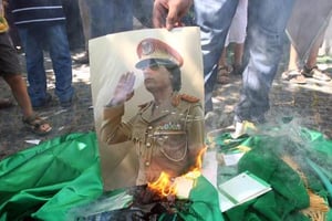 Une photo de Mouammar Kadhafi brûlée lors d’une manifestation d’opposants en 2011. © AFP