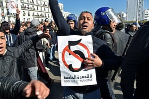 Un Algérien brandit une pancarte contre le 5e mandat que brigue le président Abdelaziz Bouteflika, lors d’une manifestation à Alger le 22 février 2019. © AFP / RYAD KRAMDI
