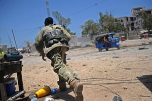Un soldat somalien se met à l’abri pendant l’attaque de ministères par les islamistes shebab, le 23 mars 2019 à Mogadiscio. © AFP / MOHAMED ABDIWAHAB