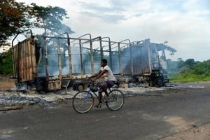 Un cycliste passe devant un camion incendié dans un village proche de Béoumi, le 17 mai 2019. © Sia KAMBOU/AFP
