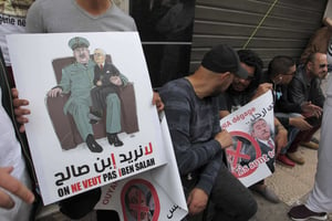 Un manifestant montrant une caricature hostile au défunt chef d’état-major Ahmed Gaïd Salah et à l’ex-président intérimaire Abdelkader Bensalah. © Fateh Guidoum/AP/SIPA