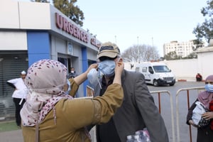 Des personnes portant des masques se tiennent à l’extérieur d’une clinique, à Alger, le 26 février 2020. © Anis Belghoul/AP/SIPA