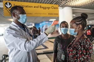 Un membre de l’Institut de santé public éthiopien prend la température d’un membre du personnel de l’aéroport à un point de contrôle, à l’aéroport international d’Addis Abeba Bole, le 17 mars 2020. © EDUARDO SOTERAS/AFP